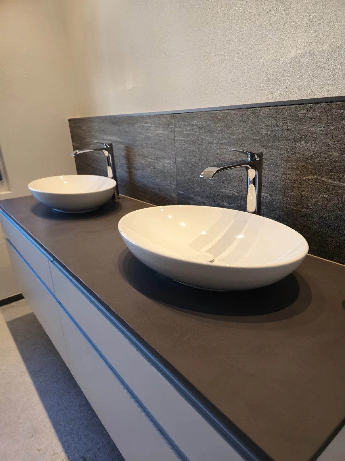 Doppel-Lavabo mit dunkler Naturstein-Rückwand - Realisiertes Bad von Hugentobler