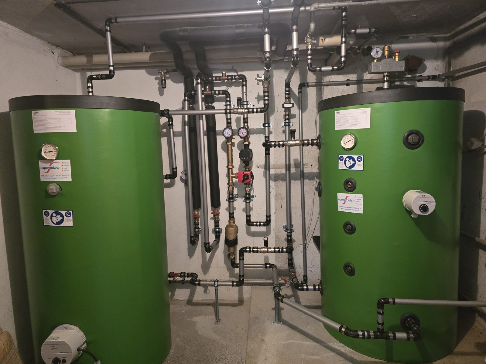 Zwei Pufferspeicher mit Verrohrung im Heizraum einer Luft/Wasser-Wärmepumpe in Uzwil