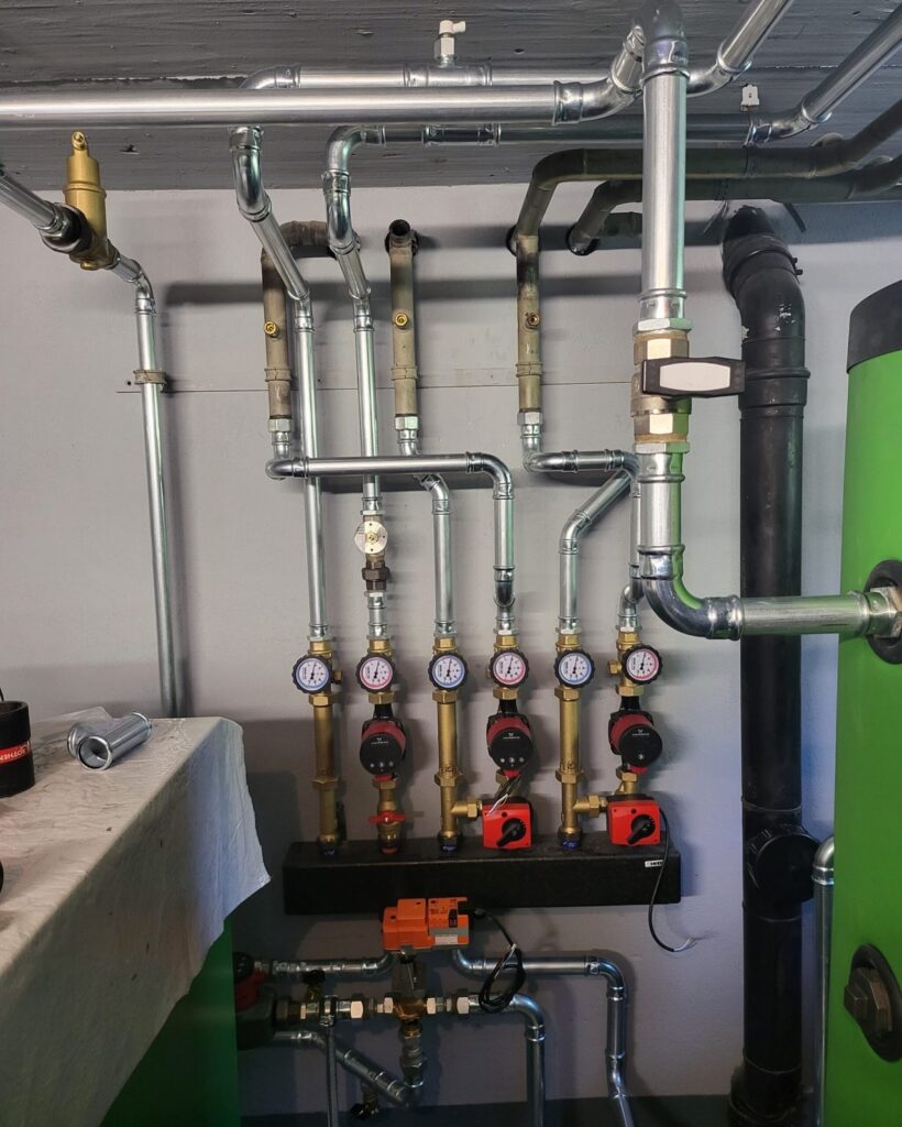 Heizungsverteiler mit sechs Pumpengruppen und Manometern im Heizraum einer Luft/Wasser-Wärmepumpe in Uzwil